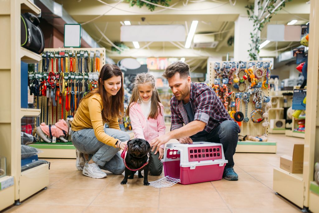 Family buying supplies for little puppy in petshop. Father, mother and dauther chooses accessories for dog in pet shop